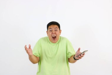 Genç Asyalı adam telefonu öfkeli bir suratla ve rahatsız edici hareketlerle tutuyor..