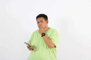 Genç adamın portresi telefon tutarken şaşkın ve şaşkın görünüyor..