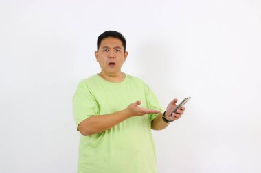 Genç adam elinde telefon tutarken şaşkın ve meraklı görünüyor..