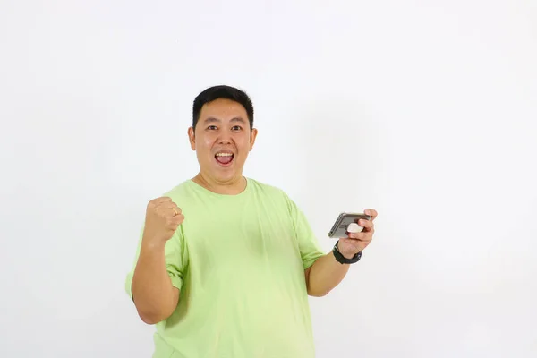 Yüzünde mutlu ve neşeli bir ifade olan Asyalı genç bir adamın portresi başarılı bir jest yapıyor.