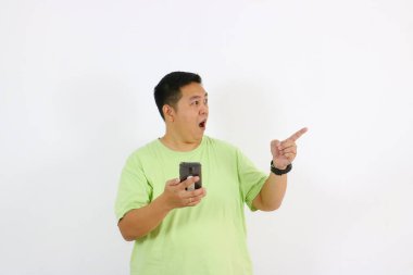 Asyalı adam cep telefonuna ve gülümseyen mutluluğa işaret ediyor