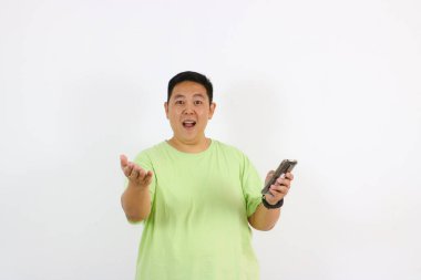 Asyalı adam elinde telefonla şaşkın bir ifade sergiliyor.