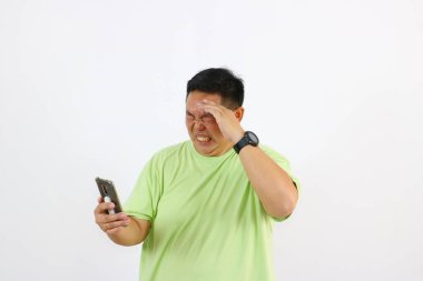 Asyalı adam telefonuna bakarken çok kötü baş ağrısı çekiyor.