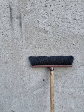 Sert beton duvara dayanan siyah tüylü ev süpürgesi.