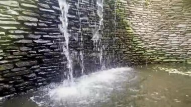 Taştan duvarda akan şelale doğal rahatlatıcı atmosfer yaratır.