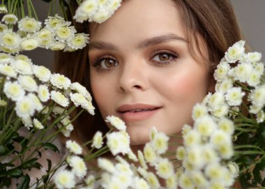 Parlak bir iç mekânda çiçeklerle güzel, nazik bir kız bahar mevsiminde taze bir görüntü.