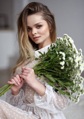 Parlak bir iç mekânda çiçeklerle güzel, nazik bir kız bahar mevsiminde taze bir görüntü.