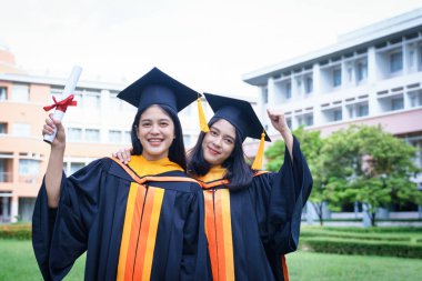 Genç Asyalı kadın üniversite mezunları sevinçle kutluyor.