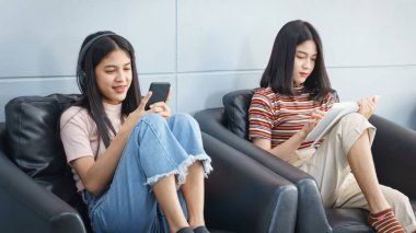 Asyalı gençler boş zamanlarını kitap okuyarak ve cel ile oynayarak geçiriyorlar.