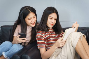 Asyalı gençler boş zamanlarını kitap okuyarak ve cel ile oynayarak geçiriyorlar.