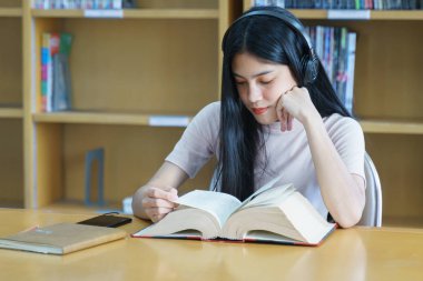 Üniversite kütüphanesinde kitap okuyan üniversite öğrencisi. 