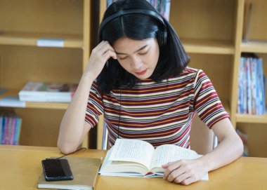 Üniversite kütüphanesinde kitap okuyan üniversite öğrencisi. 