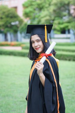 Genç Asyalı kadın üniversite mezunları, mezuniyet töreninde üniversite diploması aldıktan sonra arkadaşlarıyla keyifli ve mutlu bir kutlama yapıyor. Tebrikler, mezuniyet töreni..