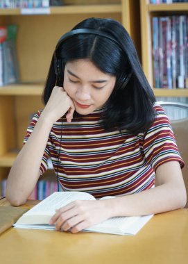 Üniversite kütüphanesinde kitap okuyan üniversite öğrencisi. 