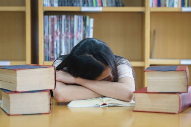 Üniversite kütüphanesinde kitap okuyan üniversite öğrencisi. 
