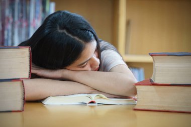 Üniversite kütüphanesinde kitap okuyan üniversite öğrencisi. 