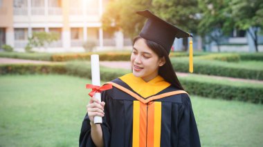 Genç Asyalı kadın üniversite mezunları, mezuniyet töreninde üniversite diploması aldıktan sonra arkadaşlarıyla keyifli ve mutlu bir kutlama yapıyor. Tebrikler, mezuniyet töreni..