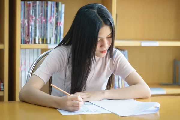 若い女子大学生は図書館内で語学練習をすることに集中しています 女子学生は試験の練習を書く — ストック写真