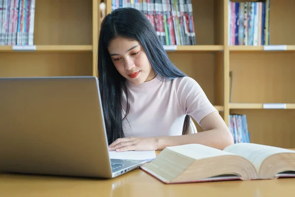 Młoda Azjatka student badania i notatki z książki w libr — Zdjęcie stockowe