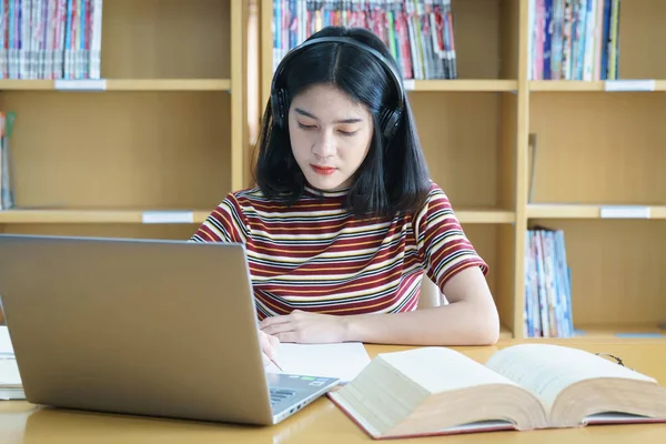 Jong aziatische vrouw student studie en maken aantekeningen met boek in libr — Stockfoto