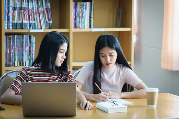 Jong aziatische vrouw student studie en maken aantekeningen met boek in libr — Stockfoto