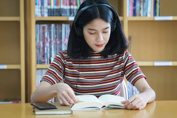 oung university student reading book in university library.