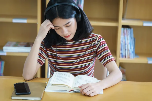 Üniversite kütüphanesinde kitap okuyan üniversite öğrencisi. 