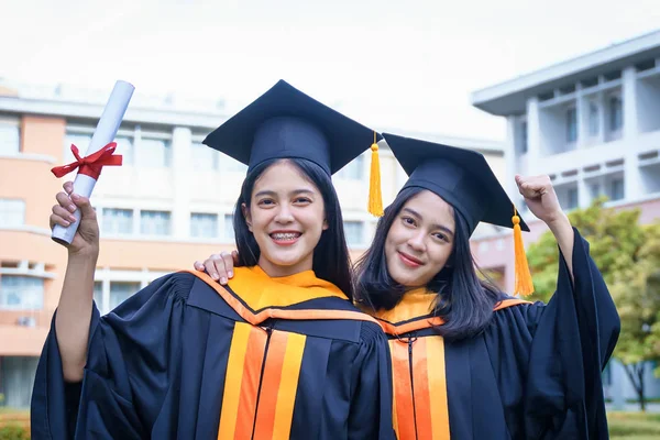 Young Asian woman university graduates celebrate with joyouse an