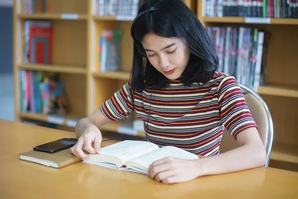 Üniversite kütüphanesinde kitap okuyan üniversite öğrencisi. 