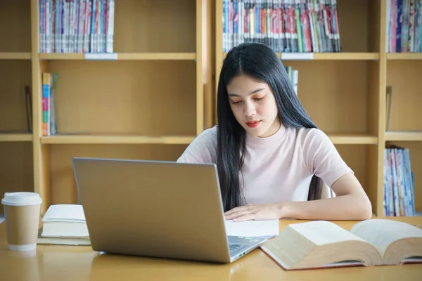 Młoda Azjatka student badania i notatki z książki w libr — Zdjęcie stockowe