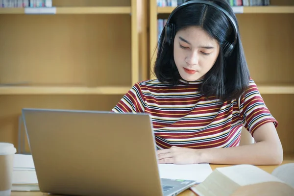 Joven mujer asiática estudiante estudio y tomar notas con libro en libr —  Fotos de Stock