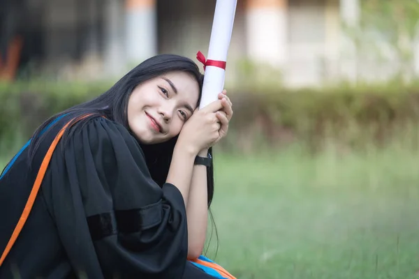 幸せな興奮した若いアジアの女性大学卒業生の肖像画は卒業のガウンを身に着けており 帽子は開始日に大学のキャンパスで学位を祝う 教育理念 — ストック写真