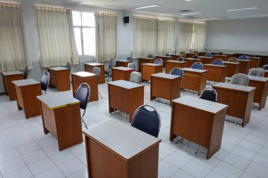 Antika ahşap sandalyeli boş bir sınıf. COVID-19 salgınını önlemek için sosyal mesafeleme konseptinde sınıf düzenlemesi. Okul konseptine dönelim..