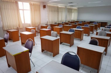 Empty classroom with vintage tone wooden chairs. Classroom arrangement in social distancing concept to prevent COVID-19 pandemic. Back to school concept. clipart