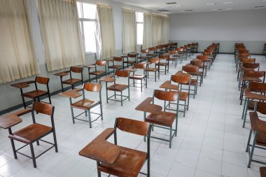 Antika ahşap sandalyeli boş bir sınıf. COVID-19 salgınını önlemek için sosyal mesafeleme konseptinde sınıf düzenlemesi. Okul konseptine dönelim..
