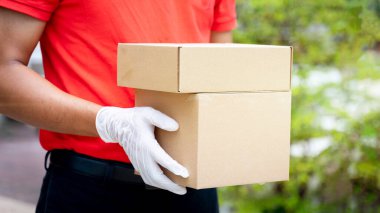 Bir teslimatçının elinde paketler ve kutular var. COVID-19 salgını sırasında online alışveriş siparişi vermek için müşterinin evinin önünde. Teslimatçı paket teslimatı yapıyor..