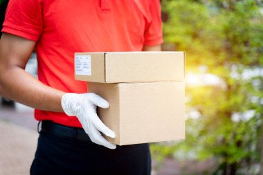 Bir teslimatçının elinde paketler ve kutular var. COVID-19 salgını sırasında online alışveriş siparişi vermek için müşterinin evinin önünde. Teslimatçı paket teslimatı yapıyor..