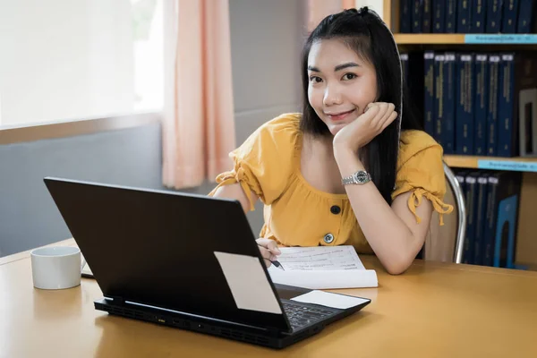 A teenager student studies online via laptop. University student girl watches online classes and writing a syllabus in notebook. Concept of distance study, online learning, webinars. Stock photo.