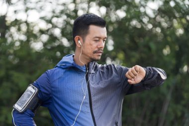 Stresli bir işten sonra akşamları şehir parkında koşan kapüşonlu bir adam. Koşucu, Forest City 'de yürüyüş antrenmanı ve egzersiz yapıyor. Stok fotoğrafı