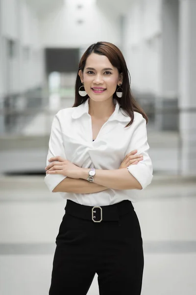 Portrait of a pretty middle age businesswoman standing Portrait of a cheerful middle-age businesswoman in business suit standing in the company building with confidence arms crossed. Modern business woman in the office with copy space. Business woman