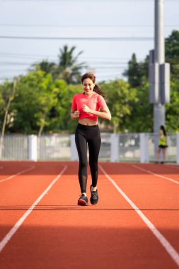 Genç fitness kadın koşucusu sabahları stadyum pistinde egzersiz yapıyor. COVID-19 salgını sırasında vücut sağlığını korumak için şehir stadyumunda kadın sporcu egzersizi. Sağlık ve Rekreasyon Stoku fotoğrafı.