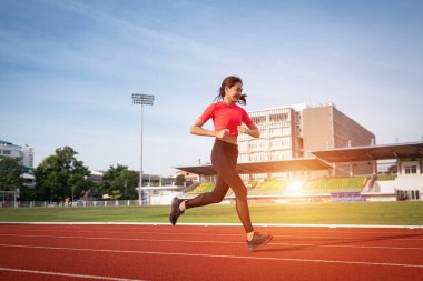 Genç fitness kadın koşucusu sabah şehir stadyumundaki pistte egzersiz yapıyor. Vücut sağlığını korumak için stadyumda kadın sporcu egzersizi. Sağlık ve Rekreasyon Stoku fotoğrafı.