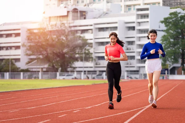 Young fitness woman runner jogging excercise in the morning on city stadium track in the city. Female athlete excercise in the city stadium to keep body fitness. Health and recreation stock photo.