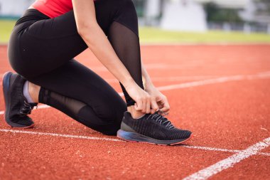 Şehir stadyumunda koşuya çıkmadan önce atletizm atletinin ayakkabı bağcığına yakın durun. Sağlıklı ve yeniden okunmuş stok fotoğrafı.
