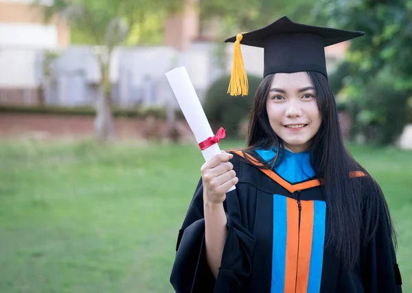 아시아인 졸업생이 행복하고 모습은 졸업식 캠퍼스에서 학위와 축하하는 가운과 모자를 — 스톡 사진