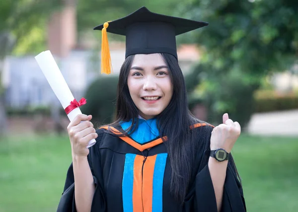 若いアジアの女性大学卒業生の幸せと興奮の肖像画は卒業のガウンと帽子を着用し 初日に大学のキャンパスで学位を祝う 教育ストックフォト — ストック写真