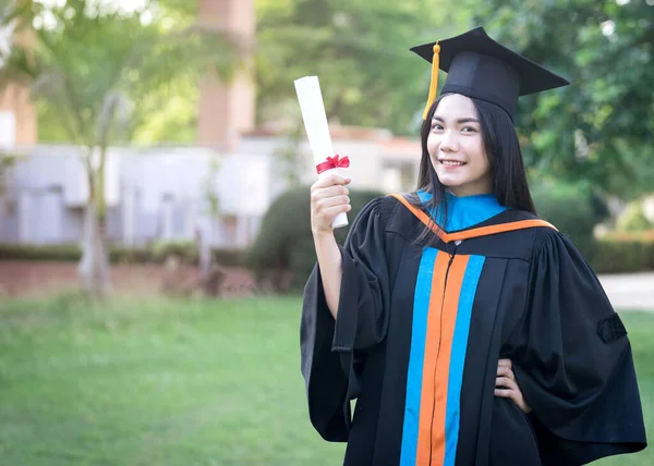 若いアジアの女性大学卒業生の幸せと興奮の肖像画は卒業のガウンと帽子を着用し 初日に大学のキャンパスで学位を祝う 教育ストックフォト — ストック写真