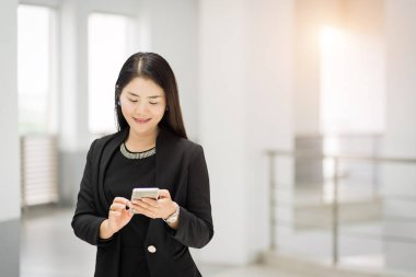 İş elbisesi içindeki neşeli ve kendine güvenen bir iş kadınının portresi iş binasında cep telefonu mesajlaşması için arama yapıyor. İş yeri fotoğrafı.