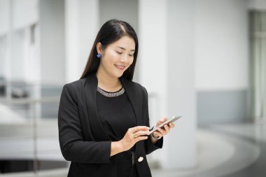 İş elbisesi içindeki neşeli ve kendine güvenen bir iş kadınının portresi iş binasında cep telefonu mesajlaşması için arama yapıyor. İş yeri fotoğrafı.