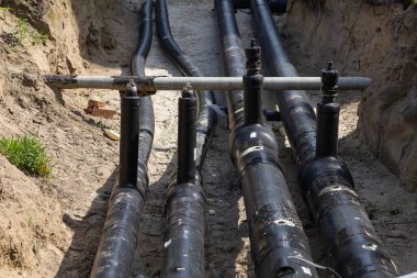 Şehir inşaatı sırasında açık siperdeki büyük siyah plastik borular. Şehir su tedarik sistemi, boru hattı bakım, onarım, altyapı ve kamu hizmetlerinin değişimi